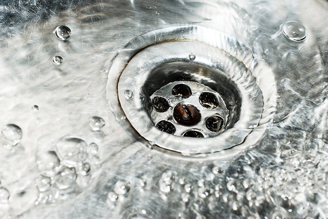 Stainless steel sink plug hole close up with water