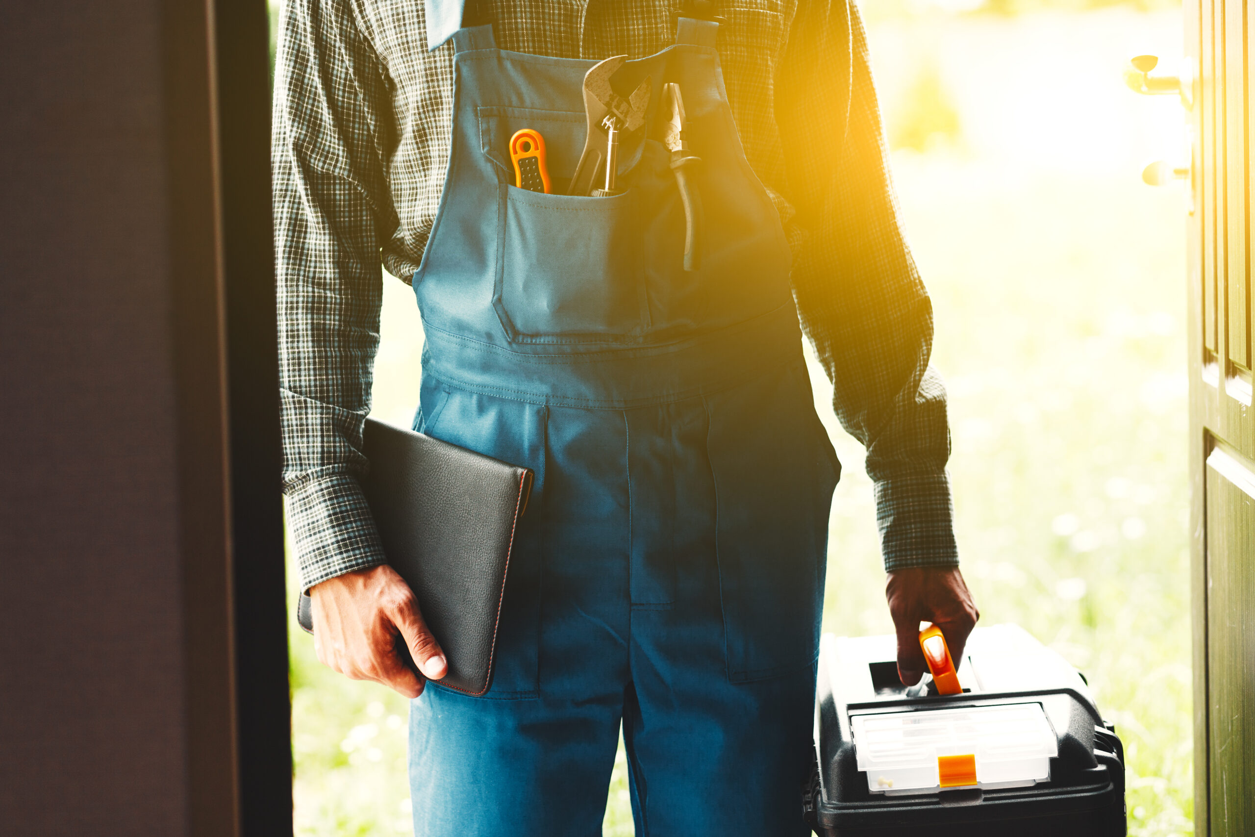 GS Plumbing - plumber standing at doorway fulfilling service plan call